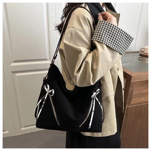 Side view of black canvas tote bag featuring metal zippers and ribbon bow accents