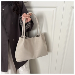 Elegante borsa tote in pelle beige con doppi manici lunghi portata da una modella