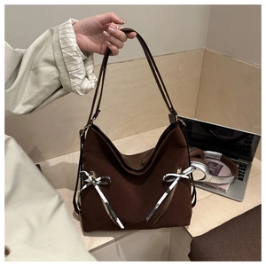 Detail of dark brown suede tote bag with zipper pockets and striped bow ribbon decor