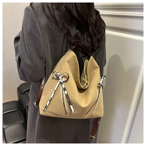Khaki canvas tote bag with bow details and brown leather straps shown on a model back view