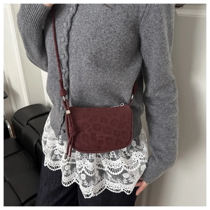 Detail of dark red suede crossbody bag with leopard print and knot tassel decor