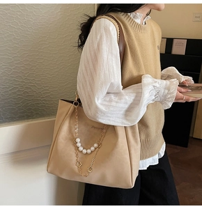 Dettaglio della borsa tote beige con catena elegante di perle sintetiche e fiori dorati