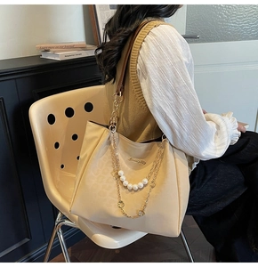 Dettaglio della borsa tote beige con motivo leopardato e catena di perle elegante