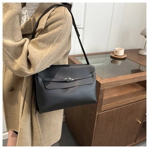Détail d'un sac porté épaule en cuir noir minimaliste avec un fermoir rotatif métallique