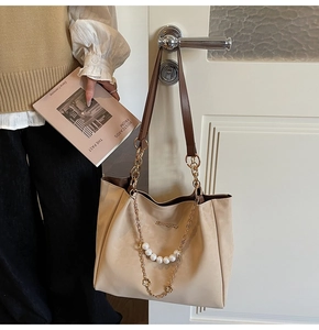 Dettaglio borsa tote in pelle crema con catena di perle e ciondolo logo in metallo dorato