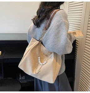 Dettaglio borsa shopper beige con tracolla di perle e ciondolo a quadrifoglio