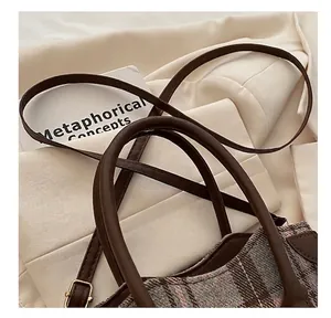 Détails macro du sac seau à carreaux avec poignées en cuir marron et finitions dorées