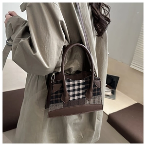 Détail d'un sac seau rétro à carreaux porté avec un trench-coat élégant et moderne