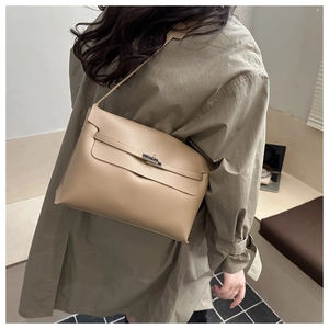 Détail d'un sac bandoulière beige en cuir avec boucle argentée porté par un mannequin