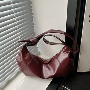 Deep burgundy leather hobo bag with unique knotted strap and minimalist crescent design