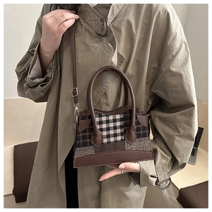 Detail van vintage geruite emmertas met bruine leren bies en verstelbare riem