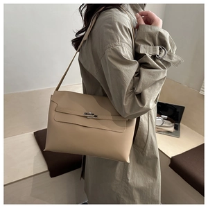 Close-up of beige leather shoulder bag with metallic twist lock and long strap detail