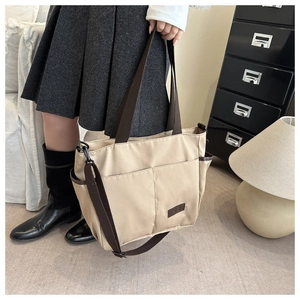 Dettaglio della borsa tote beige con tracolle marroni e grande tasca frontale esterna