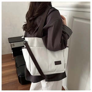 Borsa tote in tela bianca con tracolle marroni regolabili e ampia tasca frontale