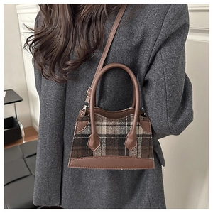 Sac seau à carreaux marron porté par un mannequin en manteau de laine