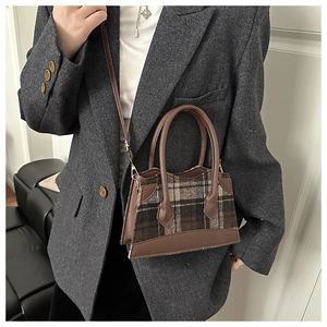 Detailopname van de vintage geruite lamswollen handtas met bruine leren biezen en handvaten