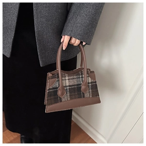 Gros plan d'un sac à main en laine à carreaux avec poignées en cuir marron pour l'hiver