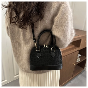 Détail du sac à main léopard avec fermeture dorée porté par un mannequin en pull