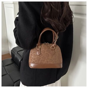 Détail d'un sac coquillage à imprimé léopard avec bordures en cuir et boucles dorées