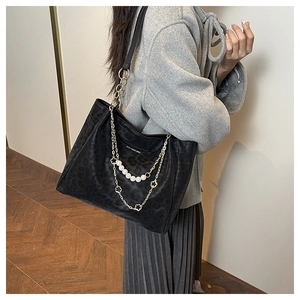 Detail of leopard print tote bag with gold chain, white pearls and clover charms