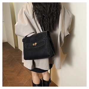 Grande borsa a spalla in pelle nera con chiusura a scatto dorata indossata da modella