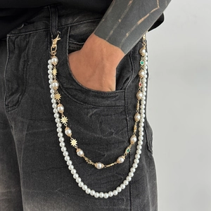 Chaîne double rang de perles et étoiles dorées portée sur un jean noir tendance