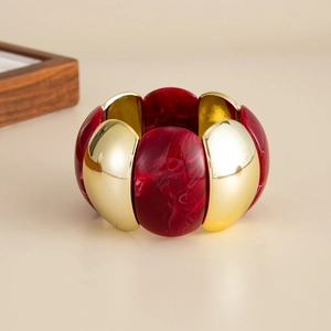 Detailed close-up of wide stretch bracelet with gold metal and red marble resin segments