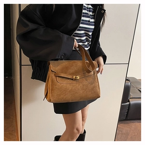 Dettaglio borsa in pelle scamosciata marrone scuro con chiusura dorata e manico in pelle