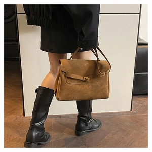 Vista laterale di una borsa a trapezio in pelle marrone vintage indossata da una modella