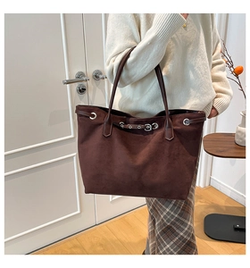 Detail of dark brown suede tote bag with metallic buckle and slim shoulder straps