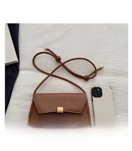 Dettaglio di una borsa in pelle marrone con fibbia dorata accanto a un telefono per la scala