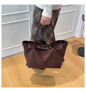 Detail of dark brown suede tote bag with metal eyelets and decorative strap buckle
