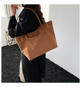 Detail of camel suede tote bag showing metal eyelets and leather buckle strap accents