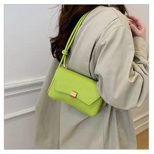 Dettaglio borsa baguette in pelle verde lime con fibbia dorata e tracolla a nodi