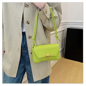 Dettaglio borsa in pelle verde neon con fibbia dorata e tracolla a nodo sul modello