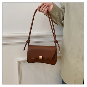 Dettaglio della borsa baguette marrone con trama in pelle e fibbia metallica dorata