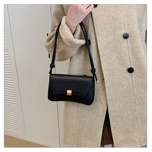 Elegante borsa in pelle nera con fibbia dorata abbinata a un cappotto di lana beige chic