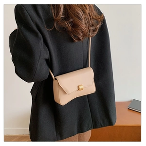 Dettaglio della borsa baguette beige in similpelle con design compatto e chiusura dorata
