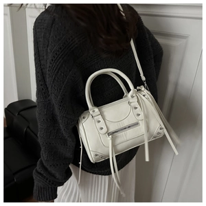 Detail of white Boston bag with silver studs, long tassels, and moto-inspired design