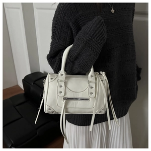Detail of white PU leather motorcycle bag with long fringe zippers and decorative rivets