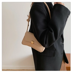 Dettaglio borsa baguette beige in pelle PU con fibbia dorata e tracolla con nodi