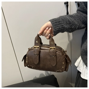 Close-up of a dark brown vintage Boston bag with gold buckle details and matte leather texture