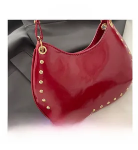 Gros plan du sac en croissant rouge avec cuir verni et détails de clous dorés