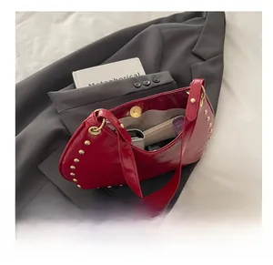 Vue interne du sac en cuir verni rouge montrant l'espace de rangement et rivets