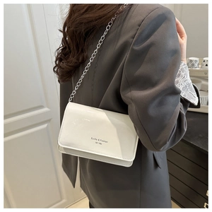 Detail van de witte glanzende PU-tas met zilveren kettingriem en minimalistische tekst