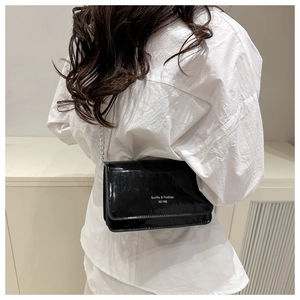 Detailweergave van de zwarte laklederen crossbody tas met zilveren ketting en witte tekst