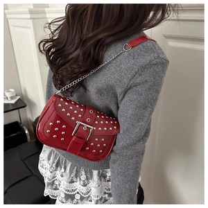 Detailed back view of a red punk style rivet shoulder bag with silver chain on model