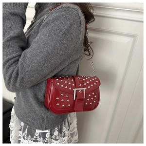 Detail of red patent leather punk bag with silver studs and metal buckle closure