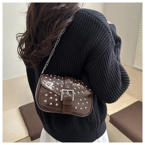 Detail of dark brown patent leather shoulder bag with silver studs and metal buckle