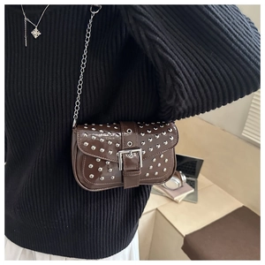 Detail view of dark brown patent leather mini bag with silver rivets and metal chain